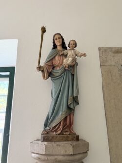 Maria segura o Menino Jesus no braço esquerdo e um cetro com coroa na mão direita.