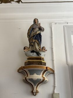 Representa a Imaculada Conceição, dogma que afirma que Maria foi concebida sem pecado original