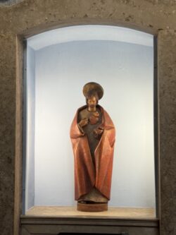 Jesus aponta para o seu coração exposto, com chamas e coroa de espinhos.